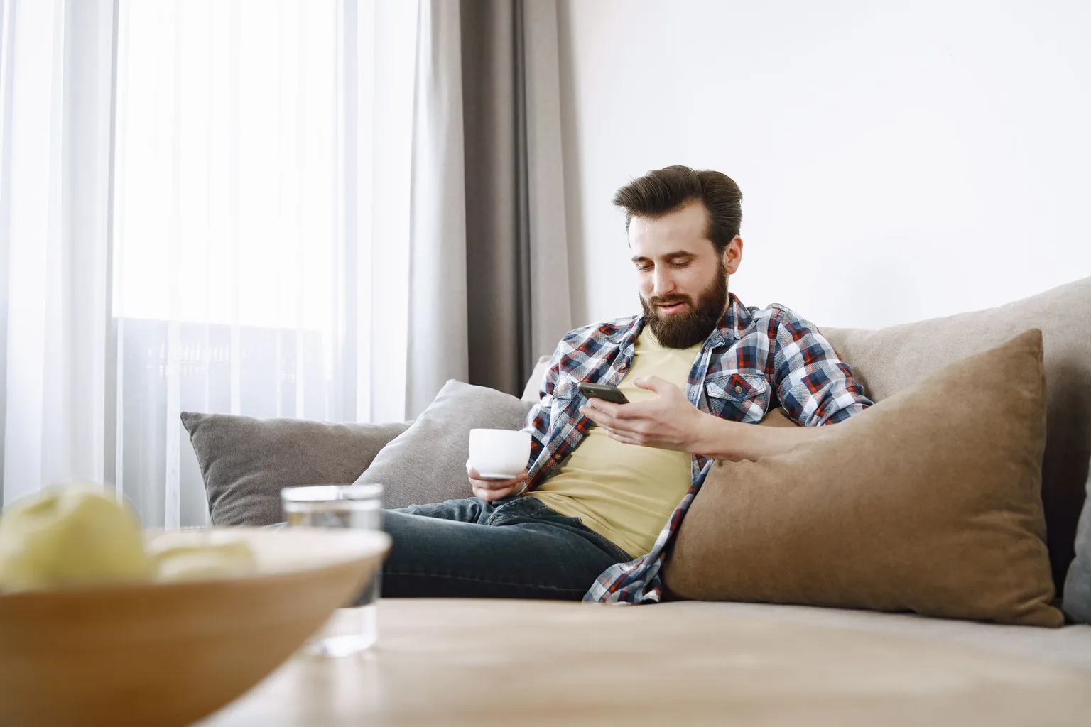Sul divano col caffè in mano, un'occhiata al telefono.